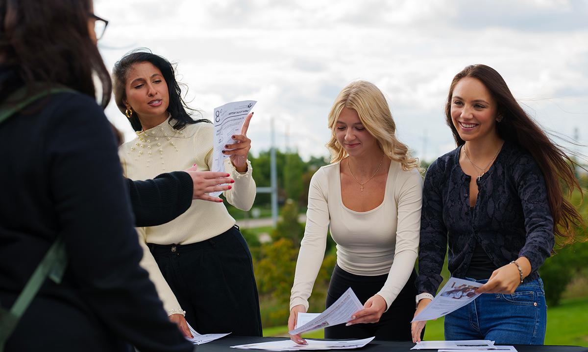 Three people at an outside table hand out flyers.